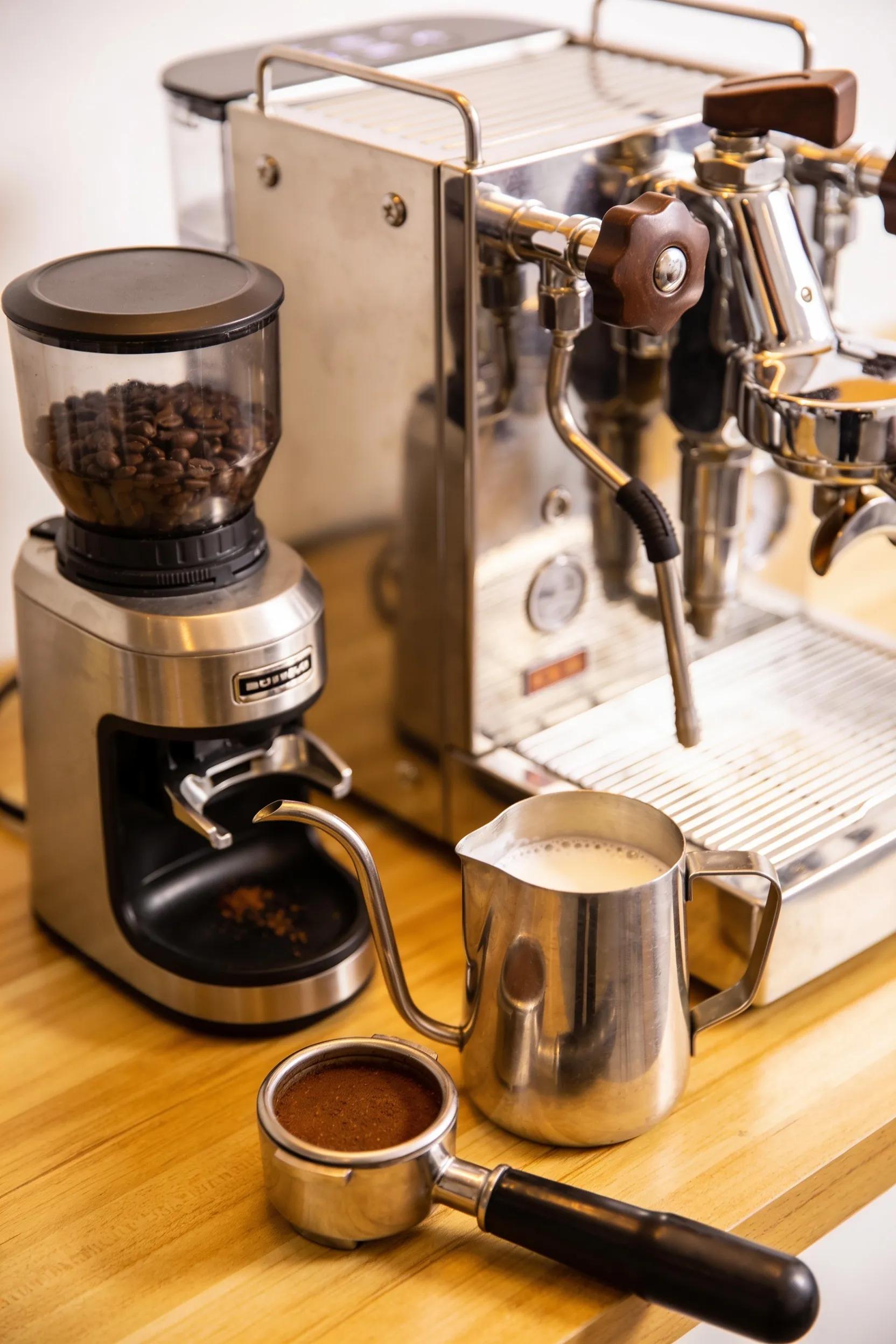 Essential tools for latte art including espresso machine, grinder, and frothing pitcher